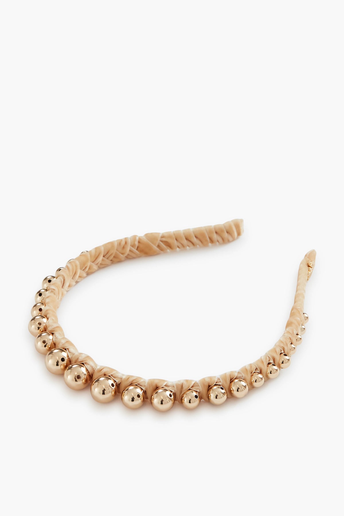 The Lele Sadoughi knotted headband is wrapped in beige fabric and features a row of gold metallic beads along the top.