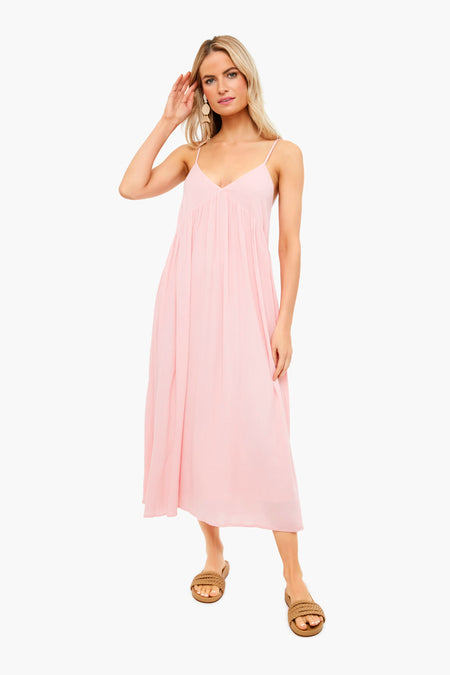 A woman showcases the elegant Atlas Midi Dress by Z SUPPLY, featuring a light pink crinkle viscose fabric with adjustable straps, paired with tan sandals.