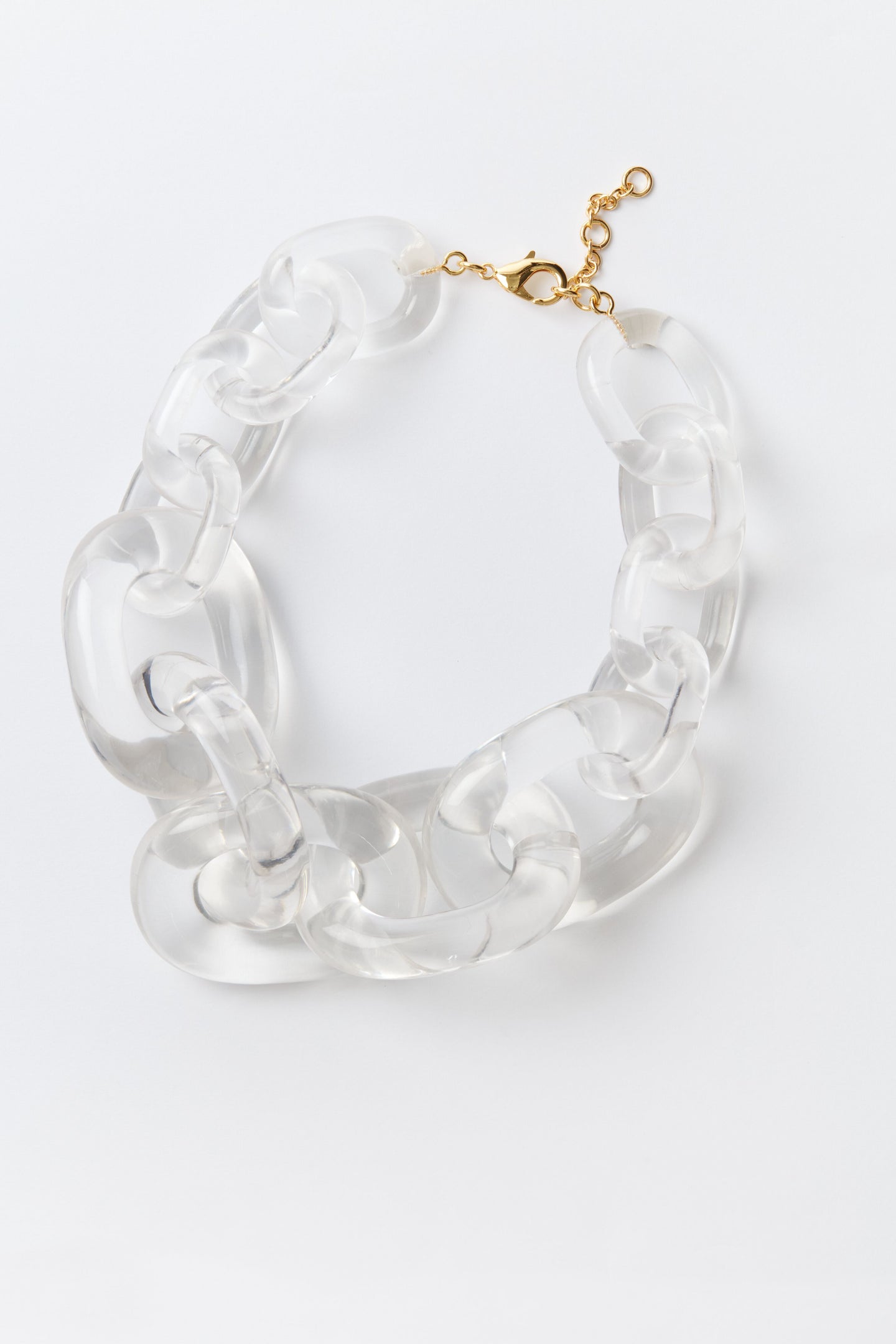 Chunky link necklace by Tuckernuck Jewelry featuring oversized clear acrylic links and a gold-tone clasp, stylishly coiled for display.