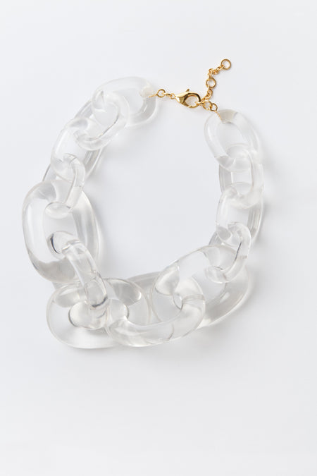 Chunky link necklace by Tuckernuck Jewelry featuring oversized clear acrylic links and a gold-tone clasp, stylishly coiled for display.