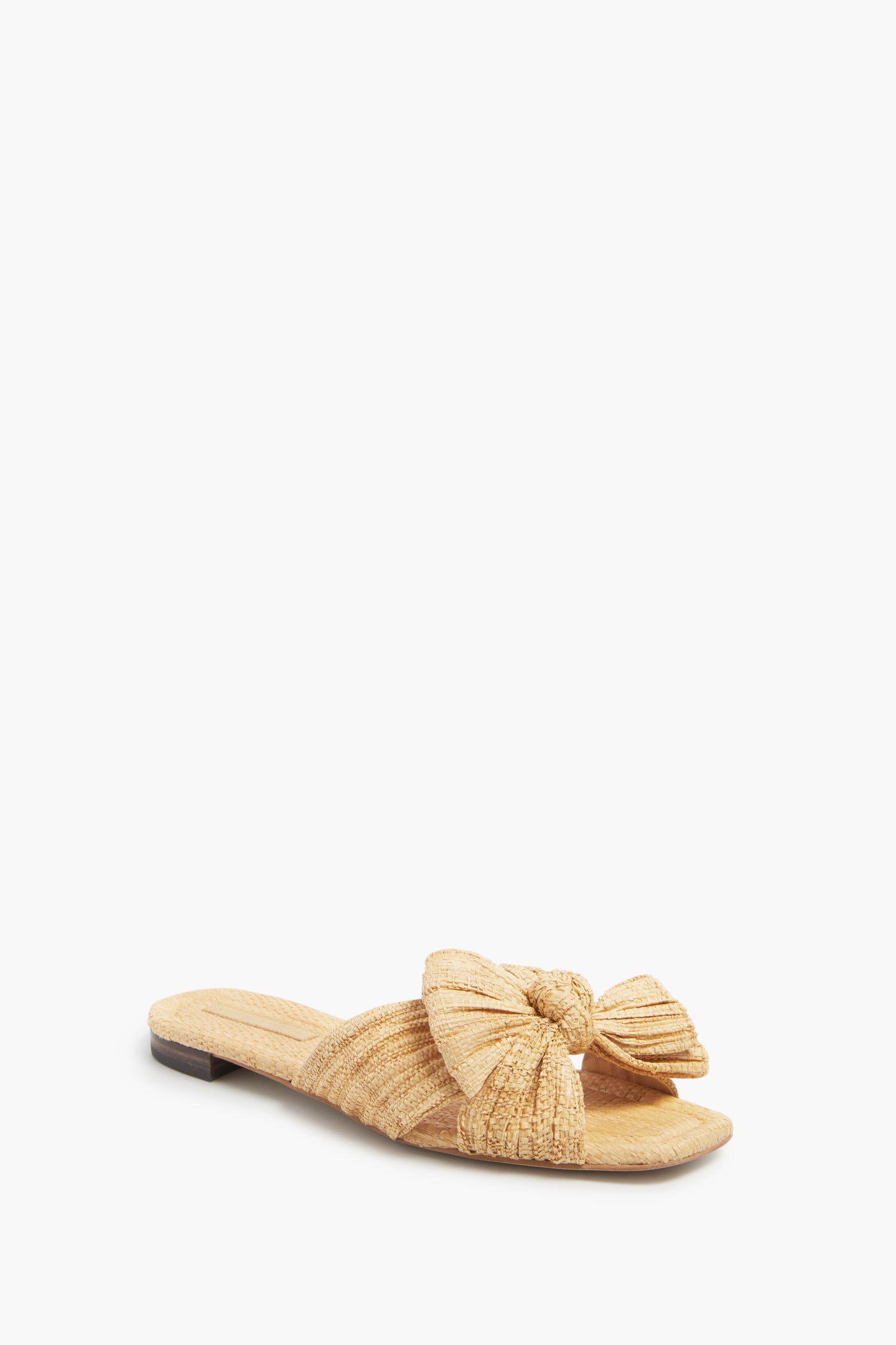 Loeffler Randall's raffia sandal features a woven straw texture, large knotted bow, flat sole, and open toe design—ideal for those seeking stylish vegan sandals.