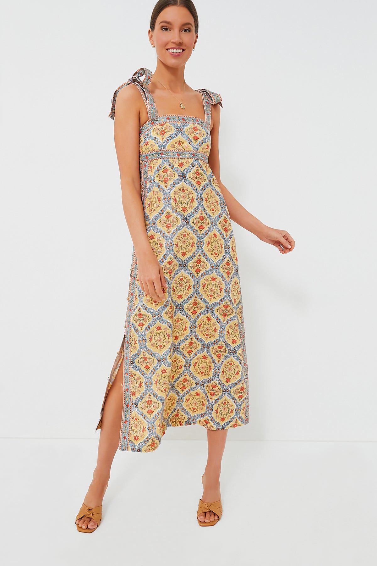 Woman wearing the Hannah Artwear Wren Tali Maxi Dress, a sleeveless patterned linen maxi with shoulder ties, side slit, and tan sandals for a feminine look.