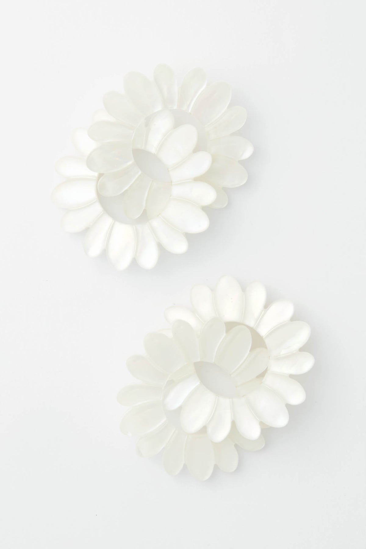 Tuckernuck Jewelry pairs two white, flower-shaped hair clips with petal designs and elegant Mother of Pearl Earrings for a charming accessory ensemble.