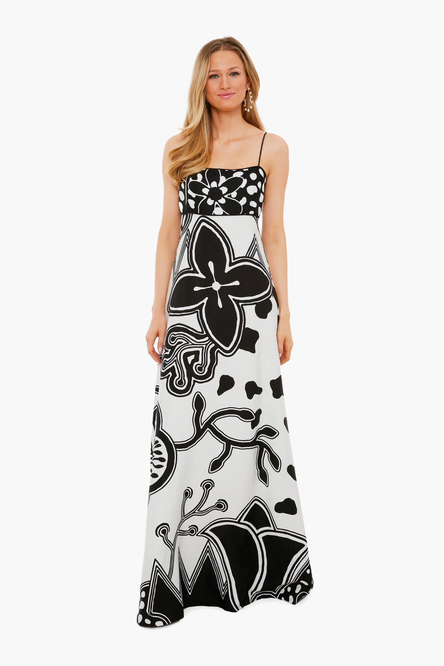 A woman wears an ALEXIS long, sleeveless dress in black and white womenswear, featuring bold floral and abstract patterns on printed twill.