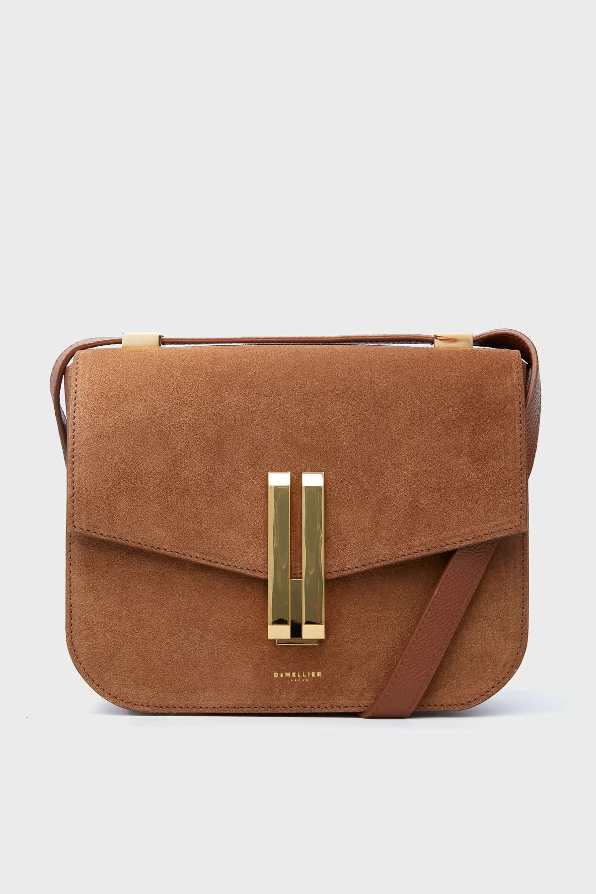 Demellier’s Tan Suede Vancouver Bag features rich brown suede, a gold rectangular clasp, and a matching leather crossbody strap—ideal for lovers of handcrafted handbags.