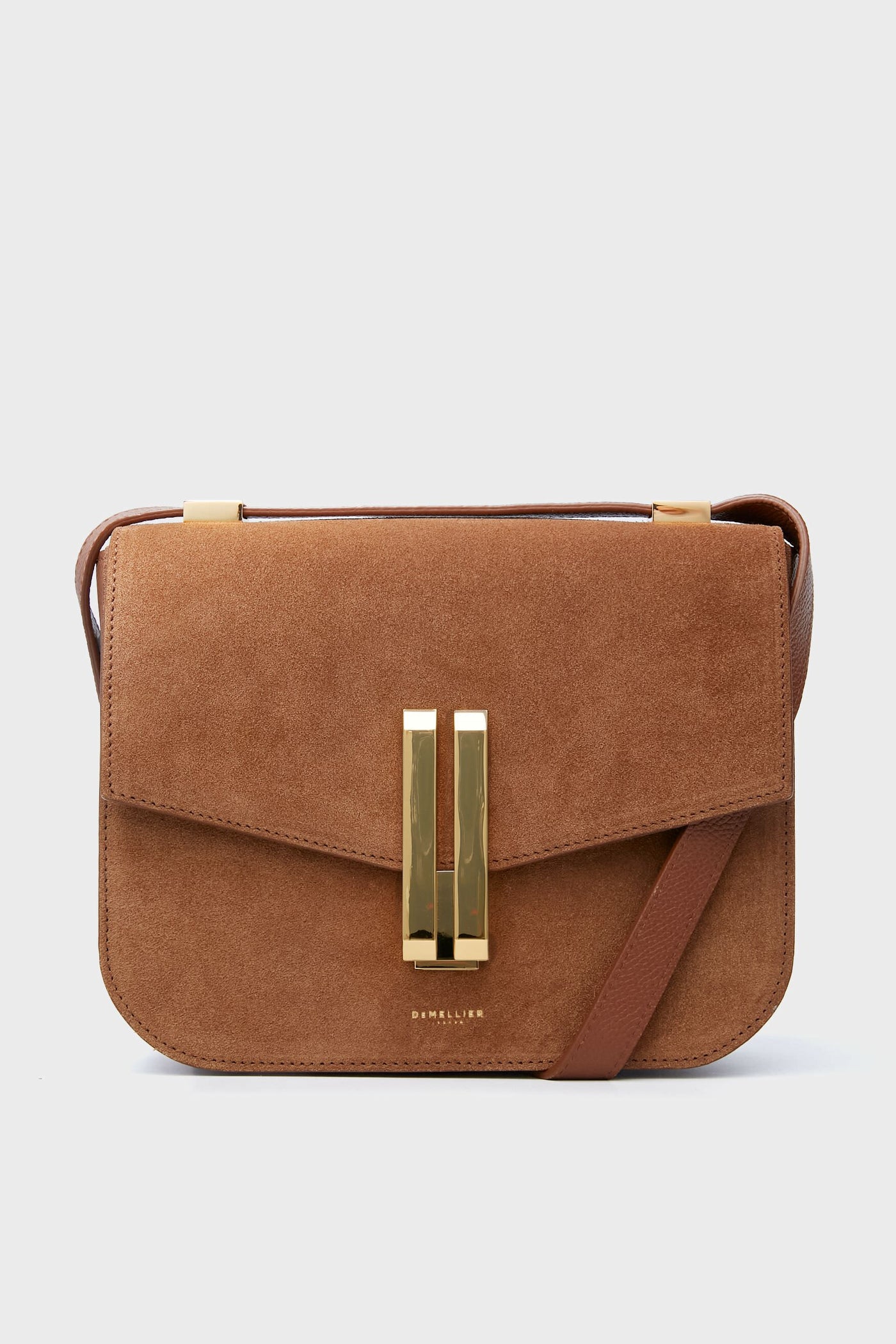 Demellier’s Tan Suede Vancouver Bag features rich brown suede, a gold rectangular clasp, and a matching leather crossbody strap—ideal for lovers of handcrafted handbags.