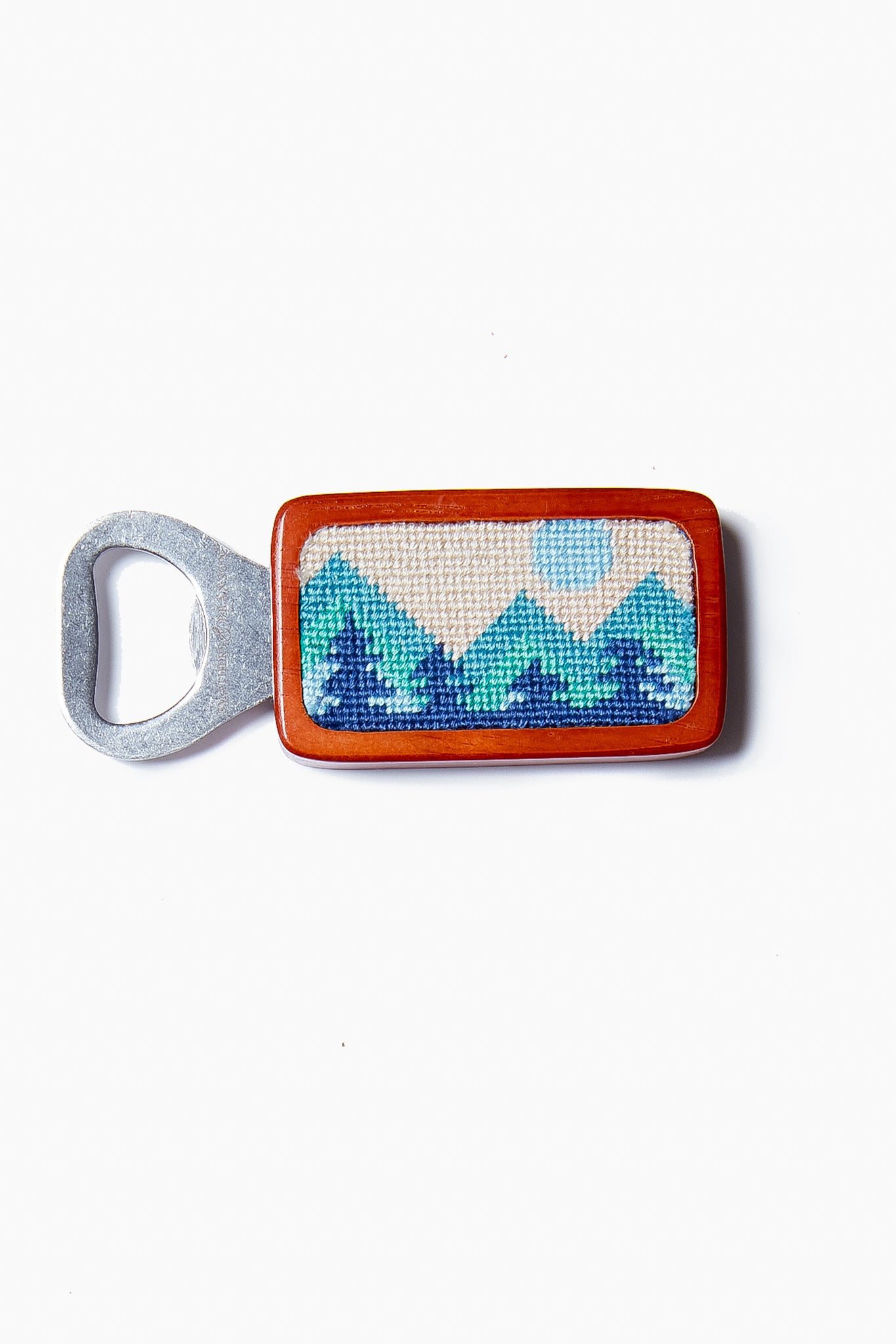 The Smathers and Branson magnetic bottle opener features a rectangular wooden handle with a hand-stitched mountain and sun design in blue and green tones.