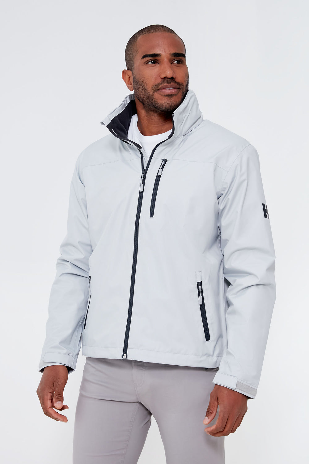 A man wearing a Helly Hansen light gray fleece-lined jacket with black zippers and a high collar over a white shirt.