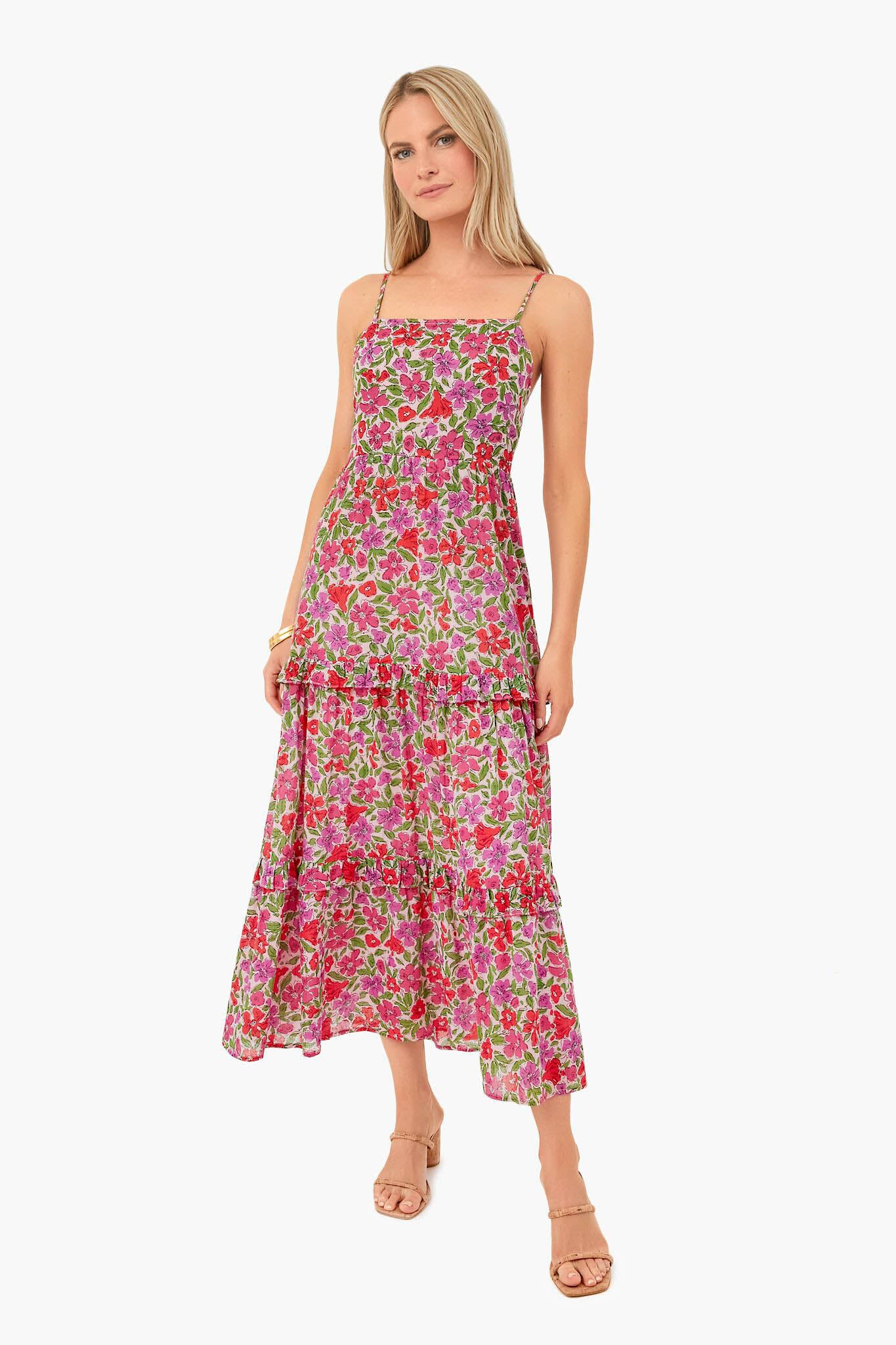 A woman wears the Banjanan Melodic Floral Bon Bon Hazel Dress, an ankle-length pink floral dress made from organic cotton voile with handmade embroidery, styled with open-toe sandals.