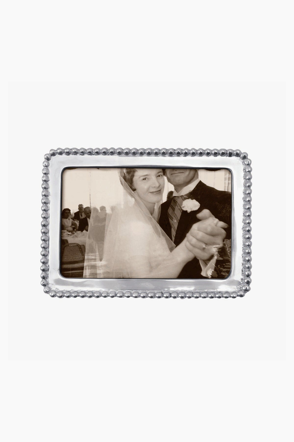 A black and white photo of a bride and groom dancing, with the groom’s face partially out of view, displayed in a Mariposa beaded recycled aluminum frame.