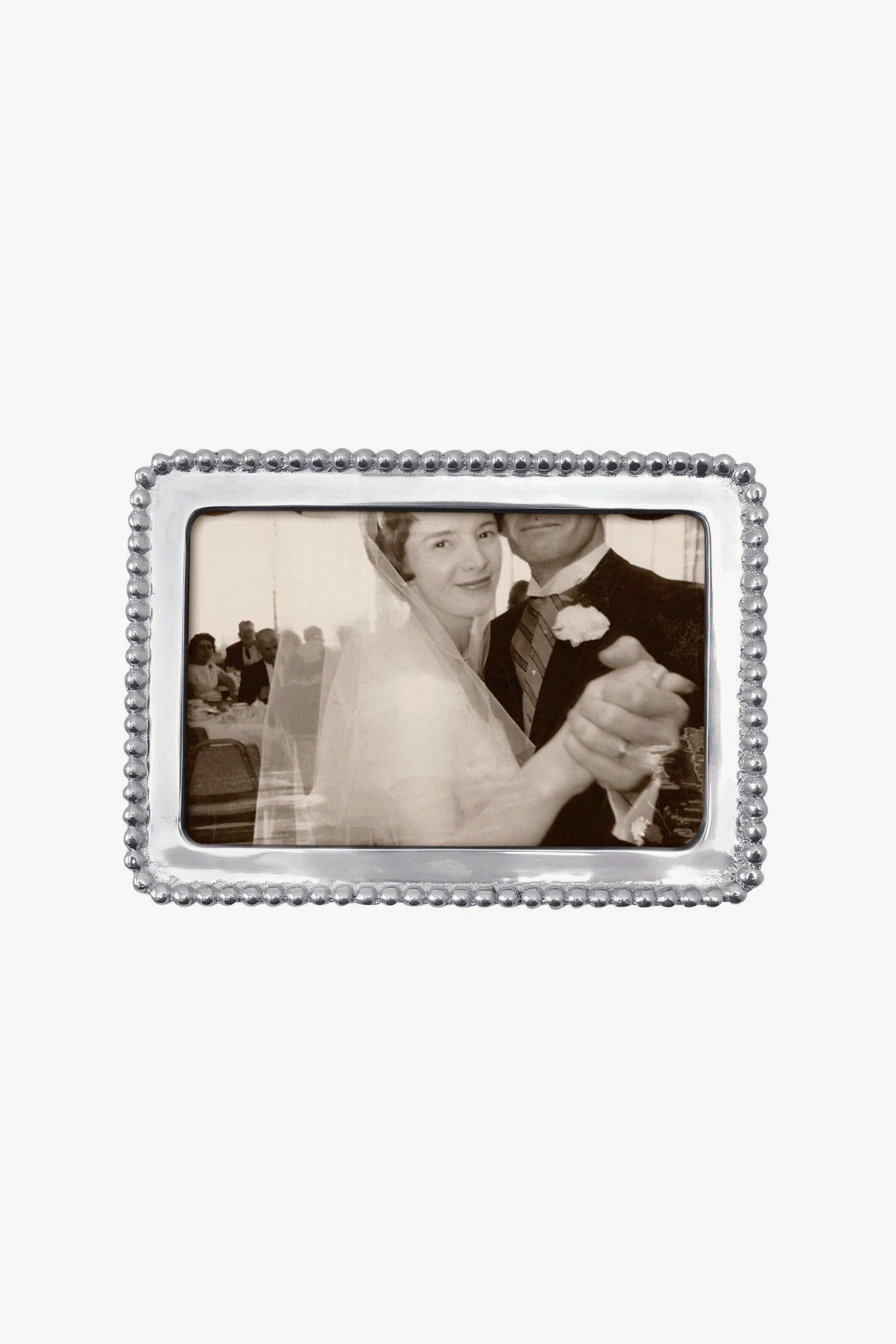 A black and white photo of a bride and groom dancing, with the groom’s face partially out of view, displayed in a Mariposa beaded recycled aluminum frame.