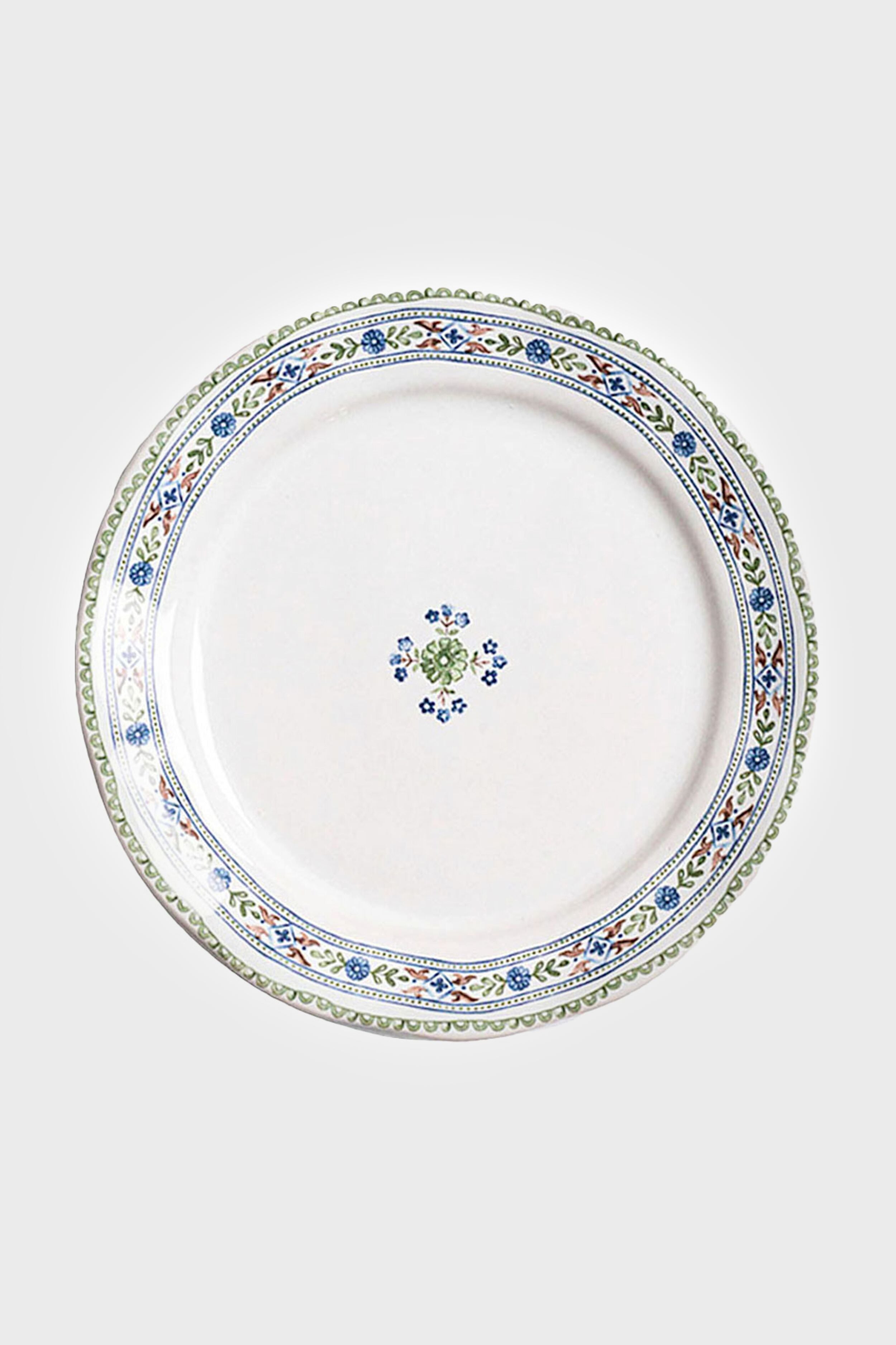White ceramic salad plate from Juliska featuring a blue, green, and yellow floral rim and a small center motif. Dishwasher safe.