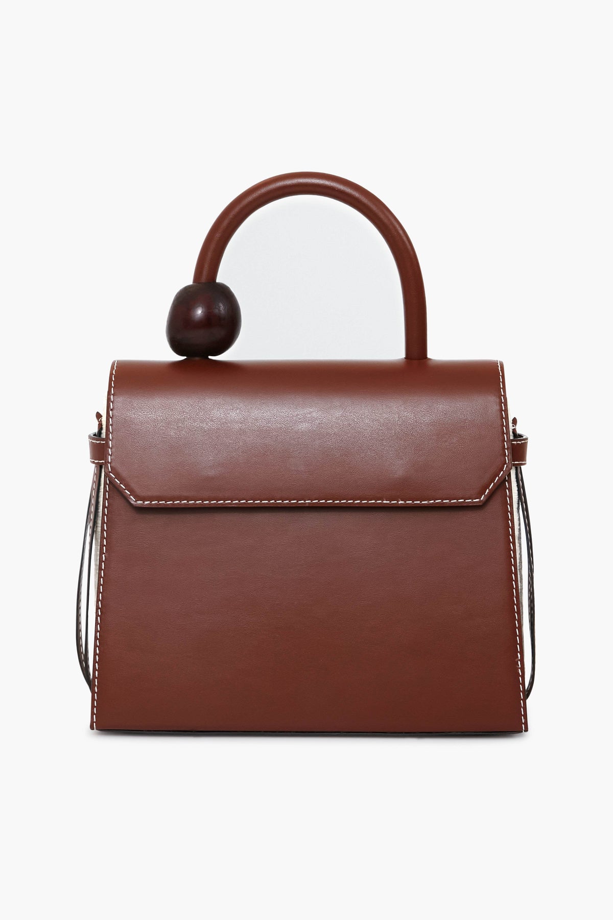 The Ballen bag is crafted from brown structured nappa leather with white stitching, a curved handle with a large round accent, and a flap closure. Luxuriously handmade in Colombia for timeless style.