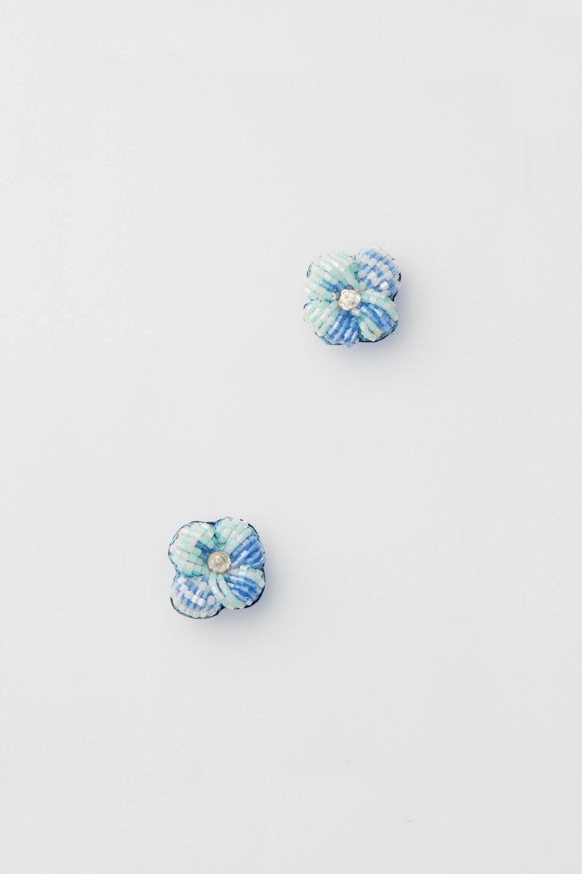 Mignonne Gavigan’s small blue and white checkered fabric flower pins with beaded centers create charming floral earrings, perfect for adding a stylish touch of beaded jewelry.