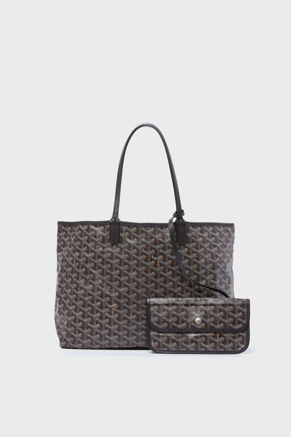 A patterned brown tote from the Tuckernuck Archive Collection features black handles and includes a matching small pouch attached in front.