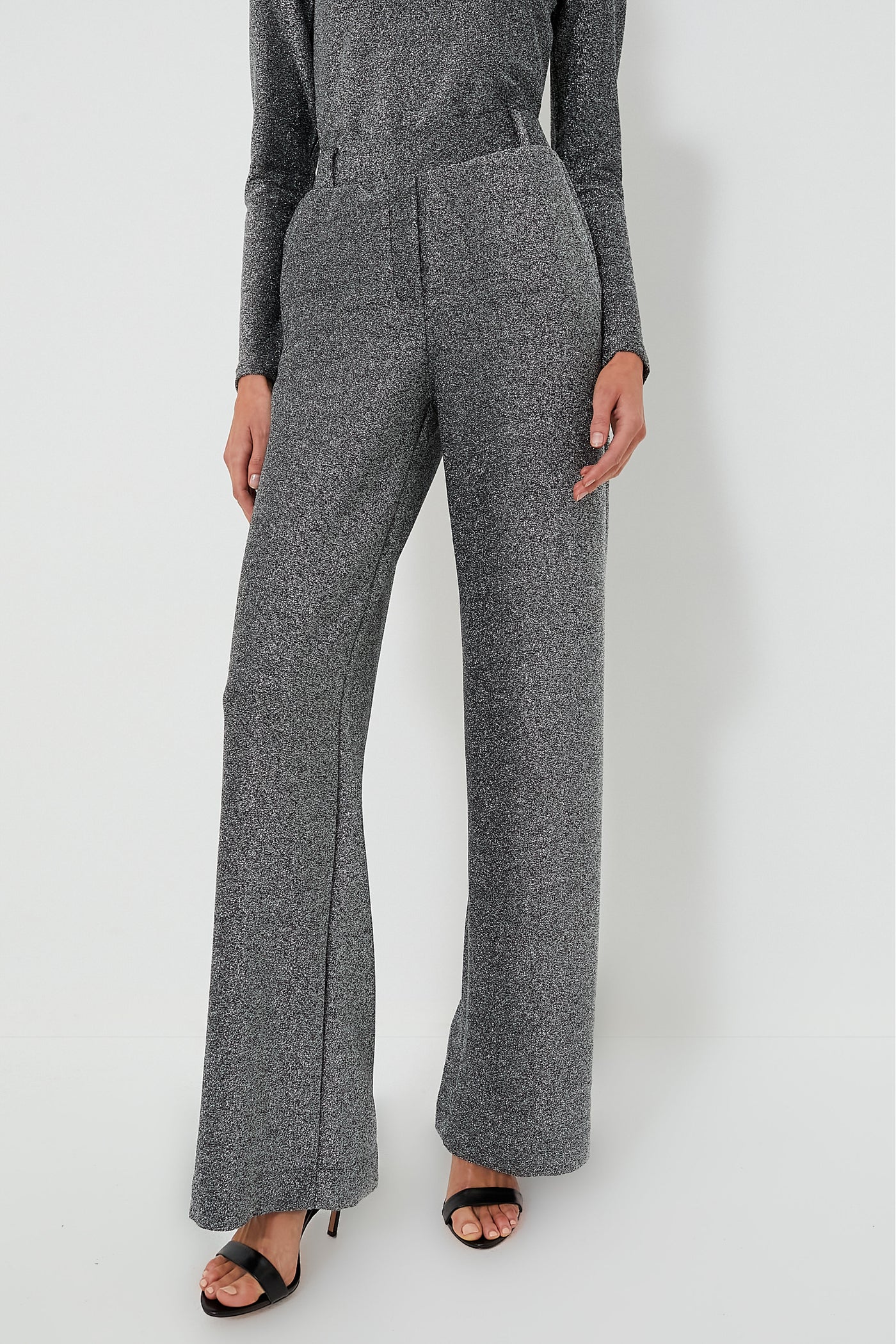 Person wearing high-waisted, wide-leg Jya Pant in Shimmer Gray from Baum Und Pferdgarten with black heeled sandals, standing confidently.