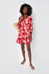 A woman models the Tnuck Beach lightweight summer dress in red with white leaf patterns, carrying a straw bag—perfect for warm days.