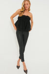 A woman wears a strapless tulle Black Willa Top by Hyacinth House, paired with black fitted pants and pointed black heels.