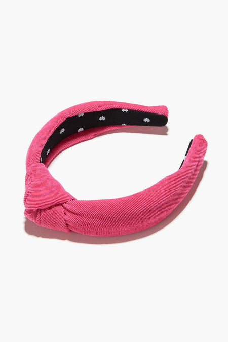 A Lele Sadoughi pink knotted headband with a black inner lining and small white floral patterns.