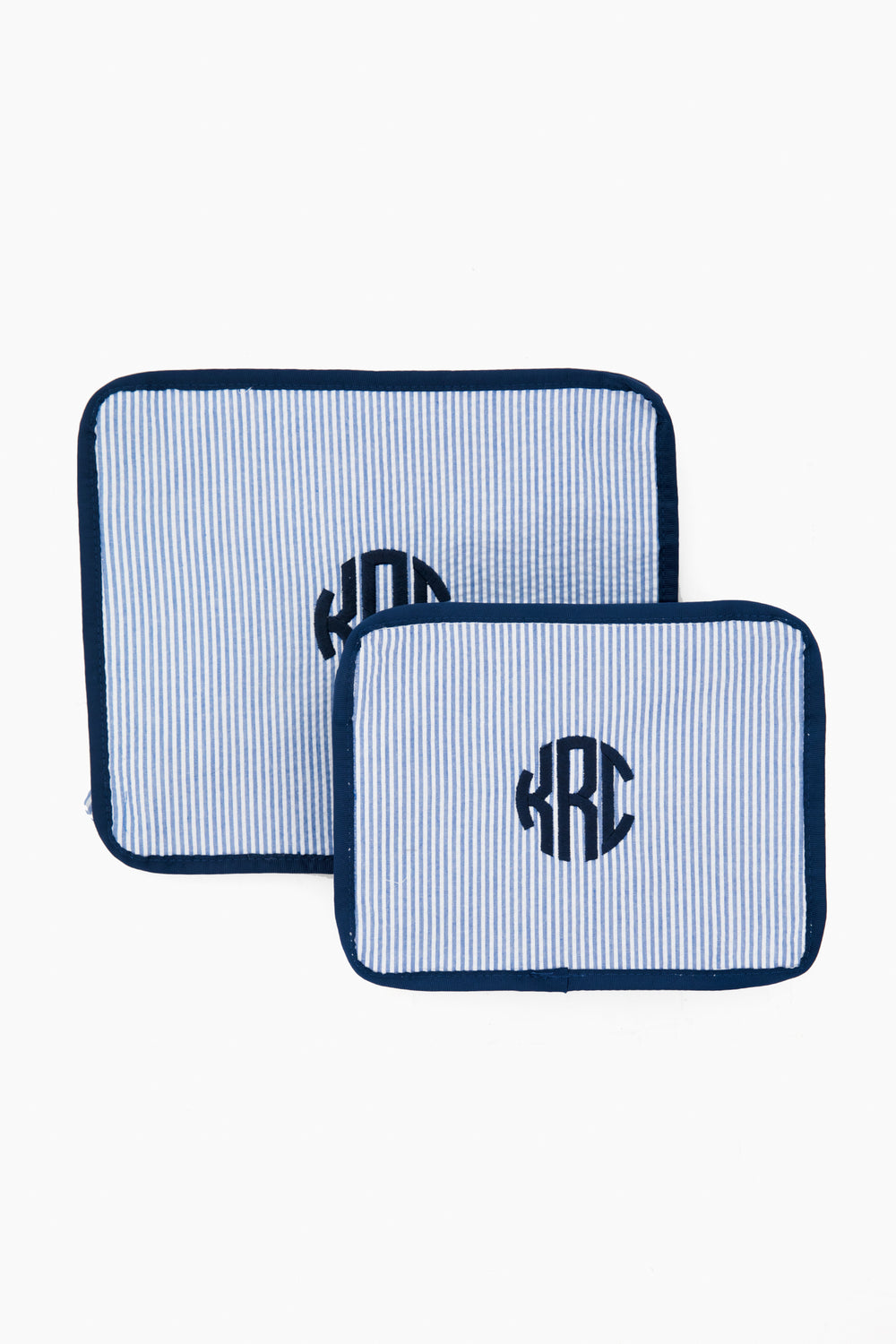 Two rectangular, blue-and-white striped fabric pouches with dark blue trim and a circular KRC monogram from Caton's Wharf—perfect as travel pouches or a thoughtful bridesmaids gift in the Blue Seersucker Travel Set.