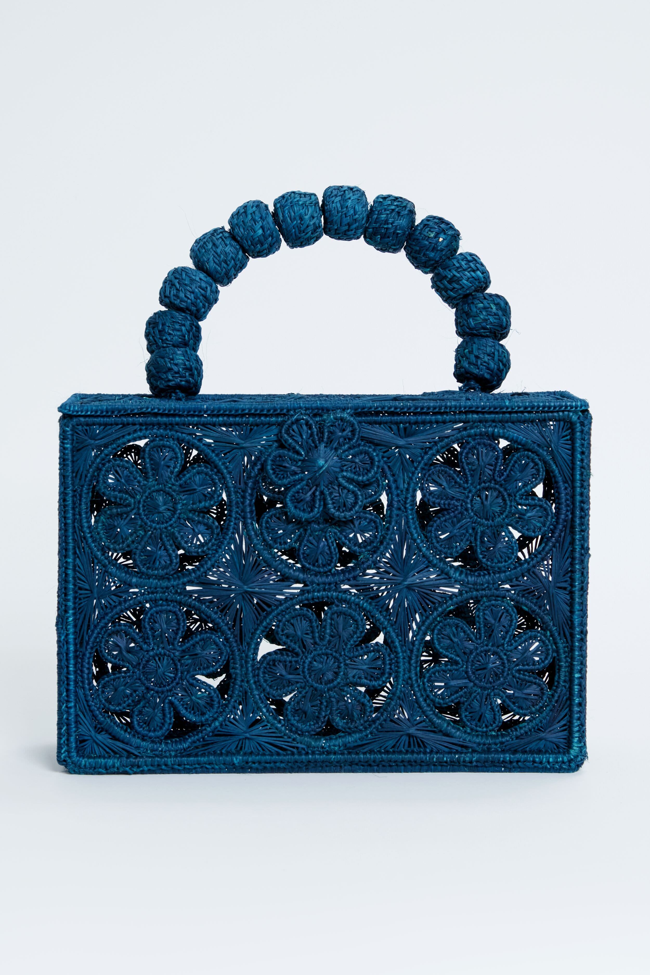 ASHA x Tuckernuck rectangular blue floral clutch with intricate cutout pattern and a handle of large woven beads—perfect for the beach.