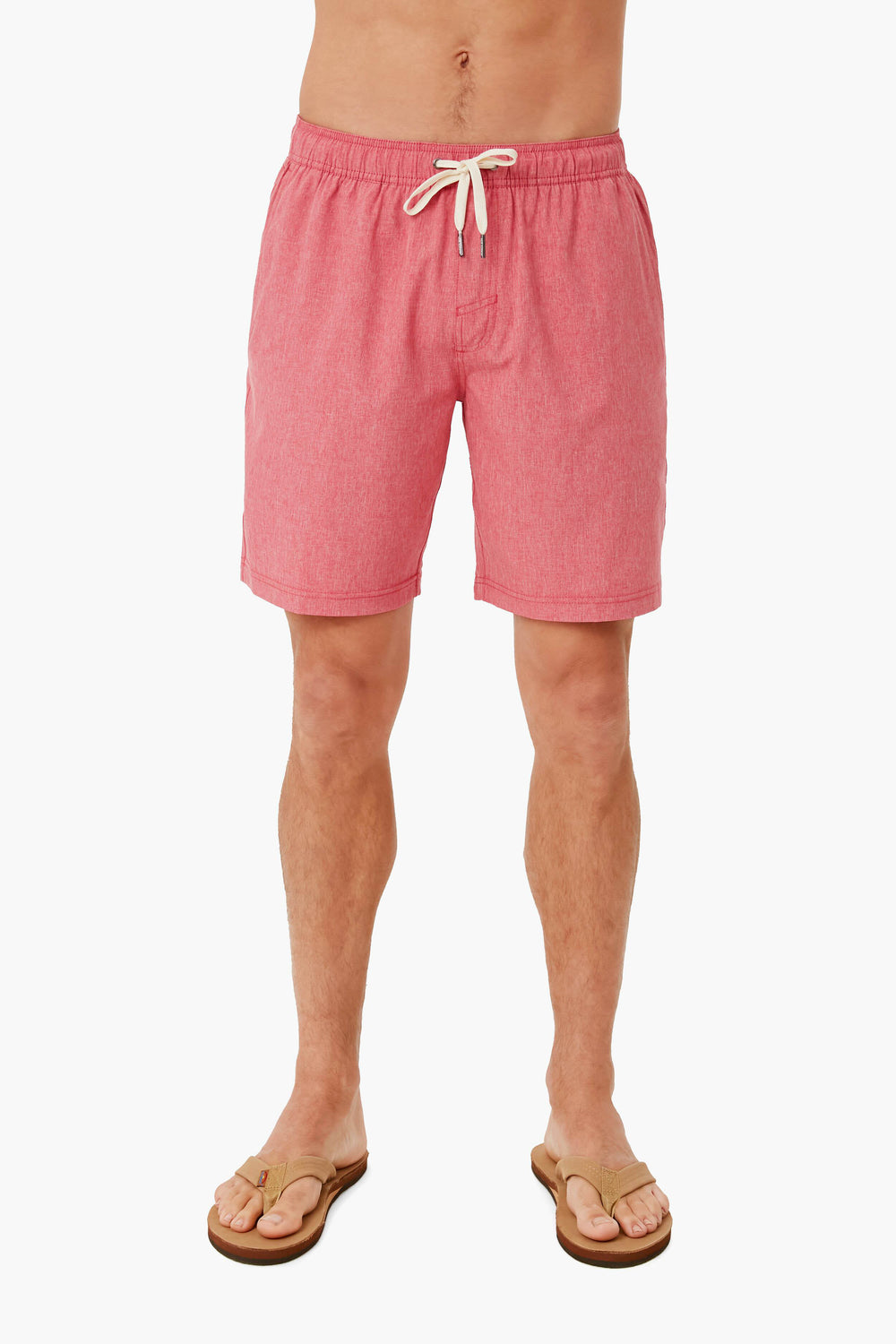 A person in pink Fair Harbor quick-drying recycled swim shorts and brown flip-flops stands confidently, showcasing the stylish look.