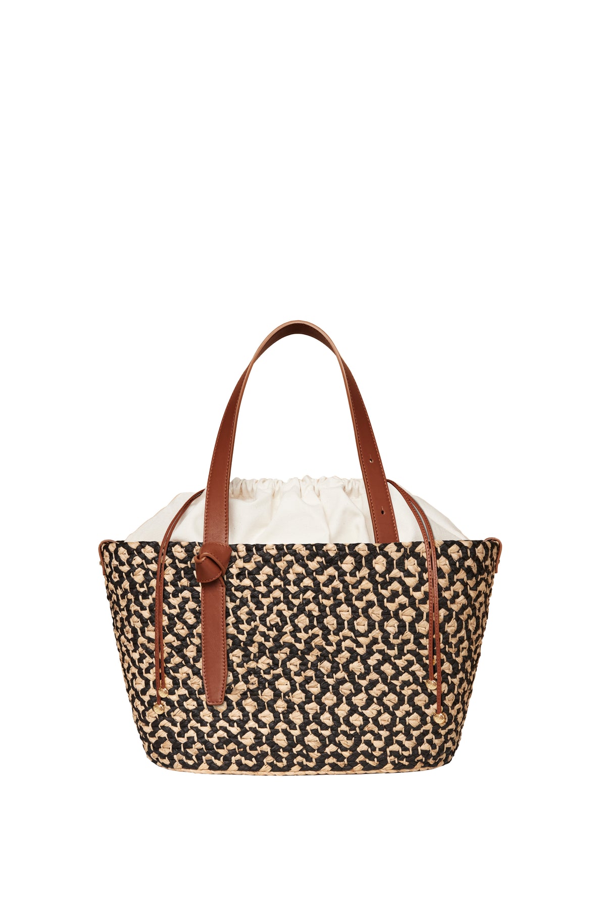 Cesta Collective handwoven raffia tote bag featuring a black and natural pattern, brown leather handles, and a white fabric drawstring lining.