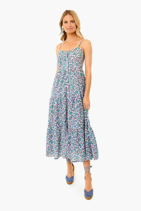 A woman stands wearing a Banjanan sleeveless, ankle-length floral sundress with spaghetti straps, handmade embroidery, and blue espadrille wedges.