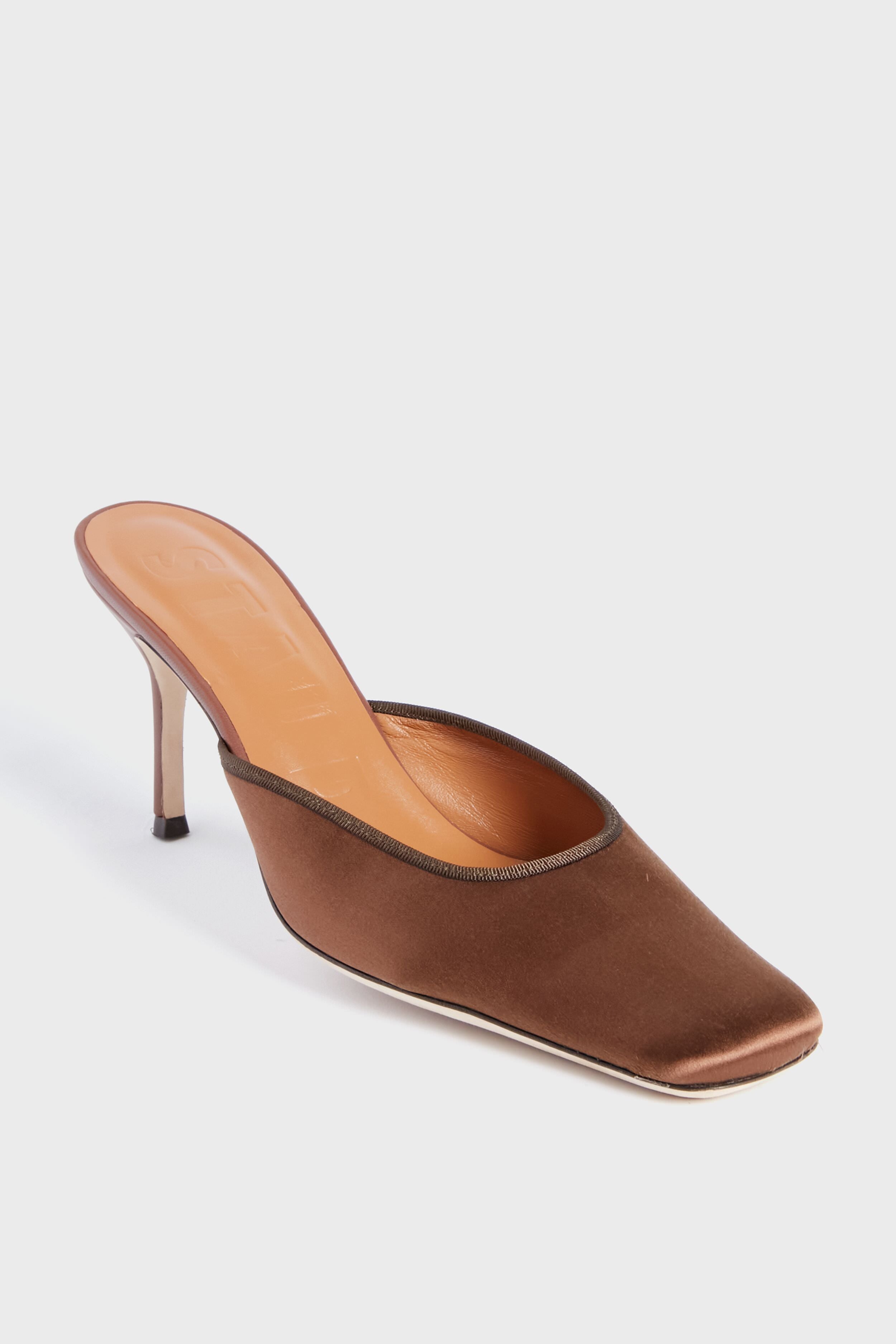 The STAUD Clove Otto Mule is a brown satin high-heeled mule with an elongated square toe and open back.