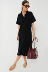 A woman in a Tuckernuck Black Channing Polo Dress crafted from lightweight stretch knit fabric.