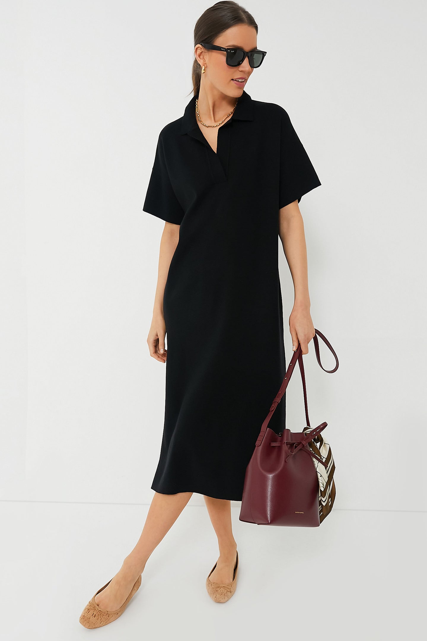 A woman in a Tuckernuck Black Channing Polo Dress crafted from lightweight stretch knit fabric.