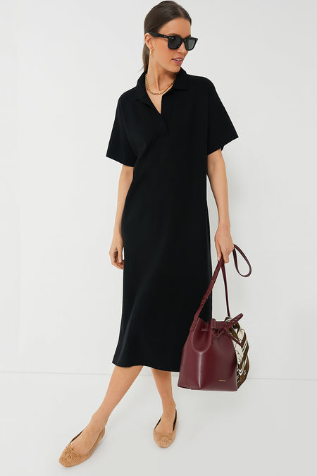 A woman in a Tuckernuck Black Channing Polo Dress crafted from lightweight stretch knit fabric.