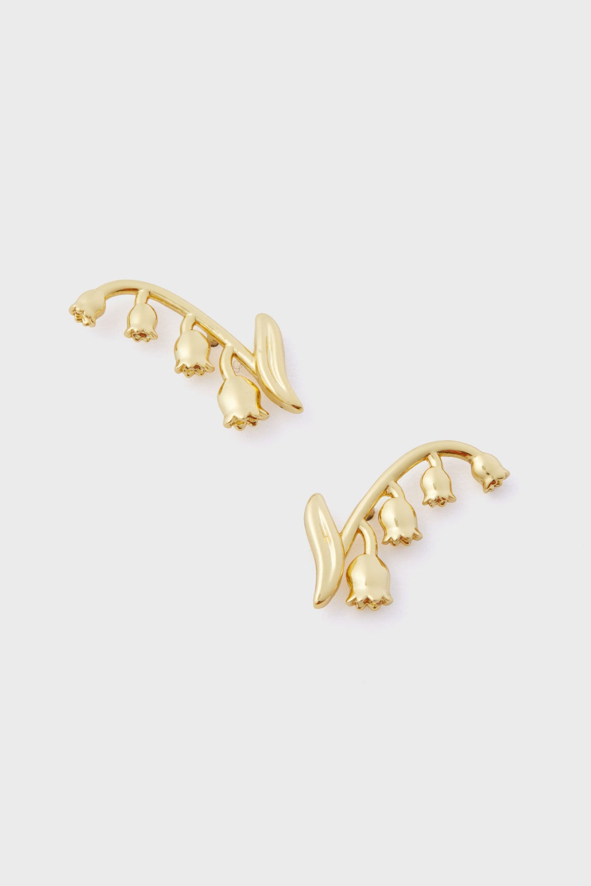 Tuckernuck Jewelry gold lily of the valley ear climber studs feature curved stems and small bell-shaped blossoms, all crafted from gold-plated brass.