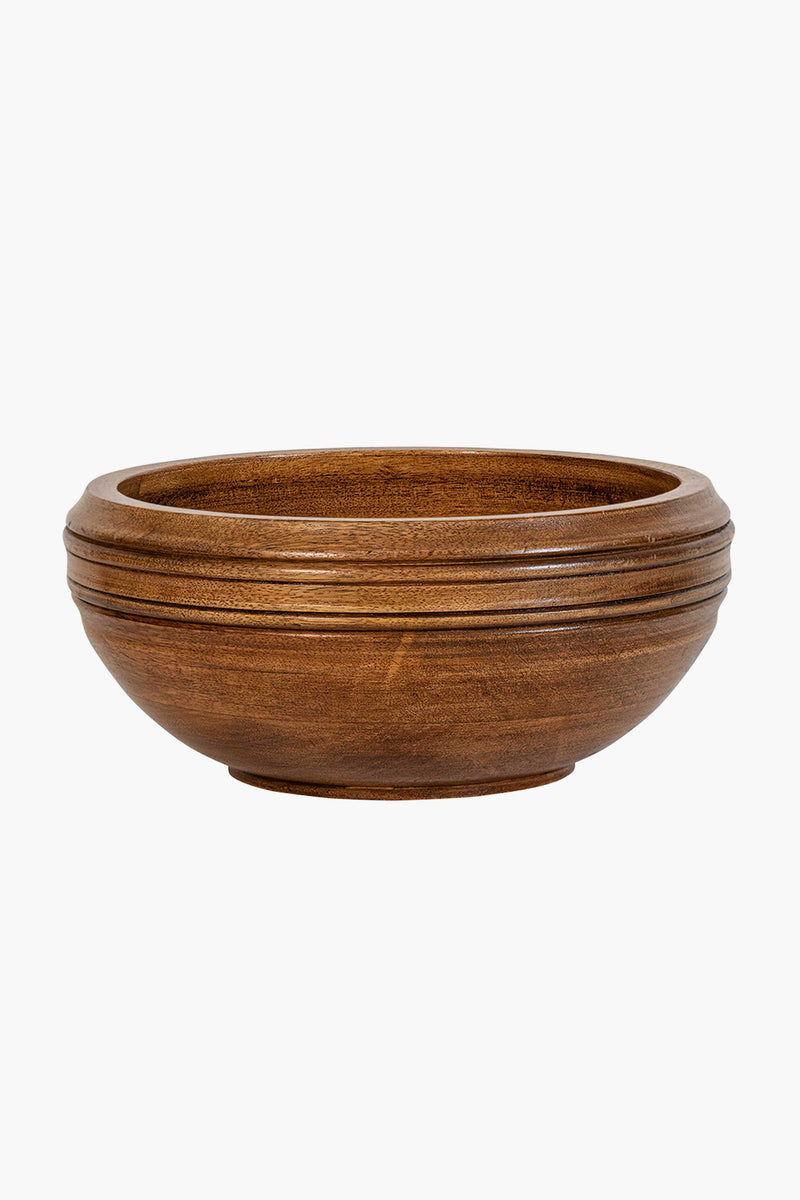 The Juliska mango wood serving bowl features a round, shallow design with a smooth finish and subtle horizontal grooves near the rim, offering an artisanal touch.
