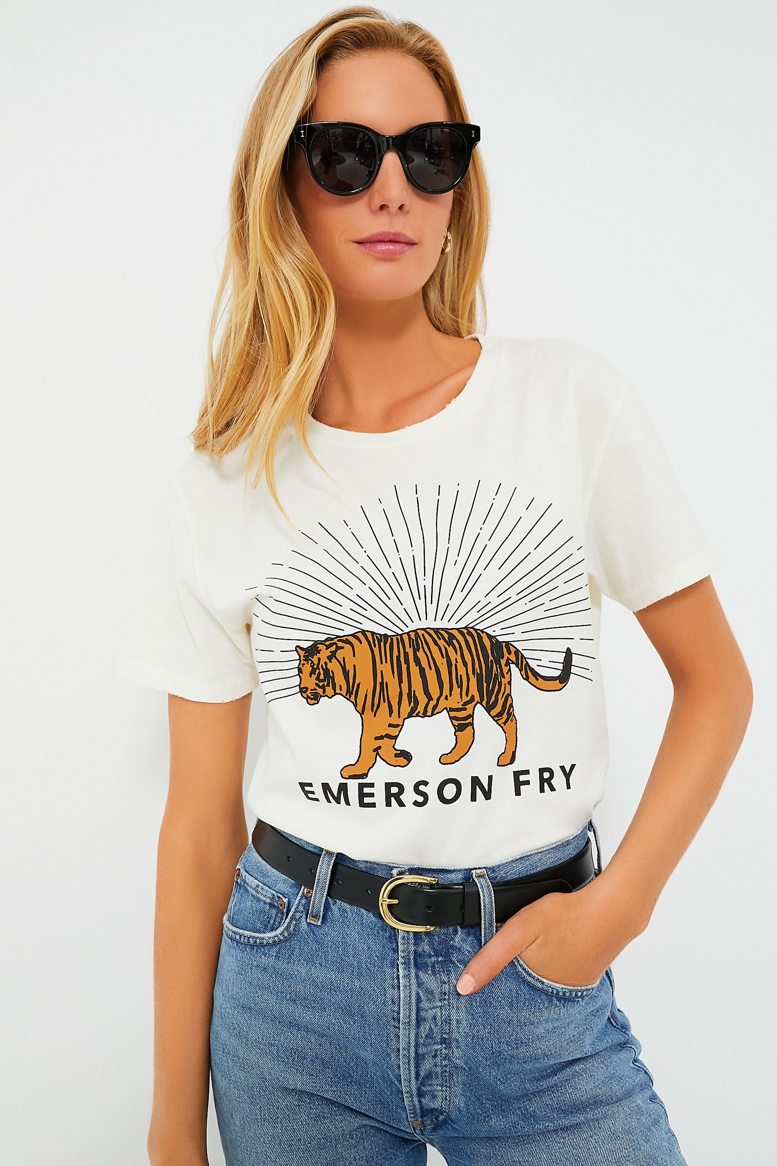 A woman wears sunglasses and the Ivory Tiger Tee by Emerson Fry—a vintage graphic tee with a tiger and EMERSON FRY text—paired with blue jeans and a black belt.