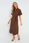 A woman wears a Tuckernuck chocolate brown, short-sleeve, band collar, belted midi button-down dress paired with wedge sandals.