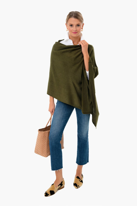 A woman stands confidently in a green breezy Poncho by Pomander Place, white shirt, blue cropped jeans, patterned loafers, and holding a woven handbag.