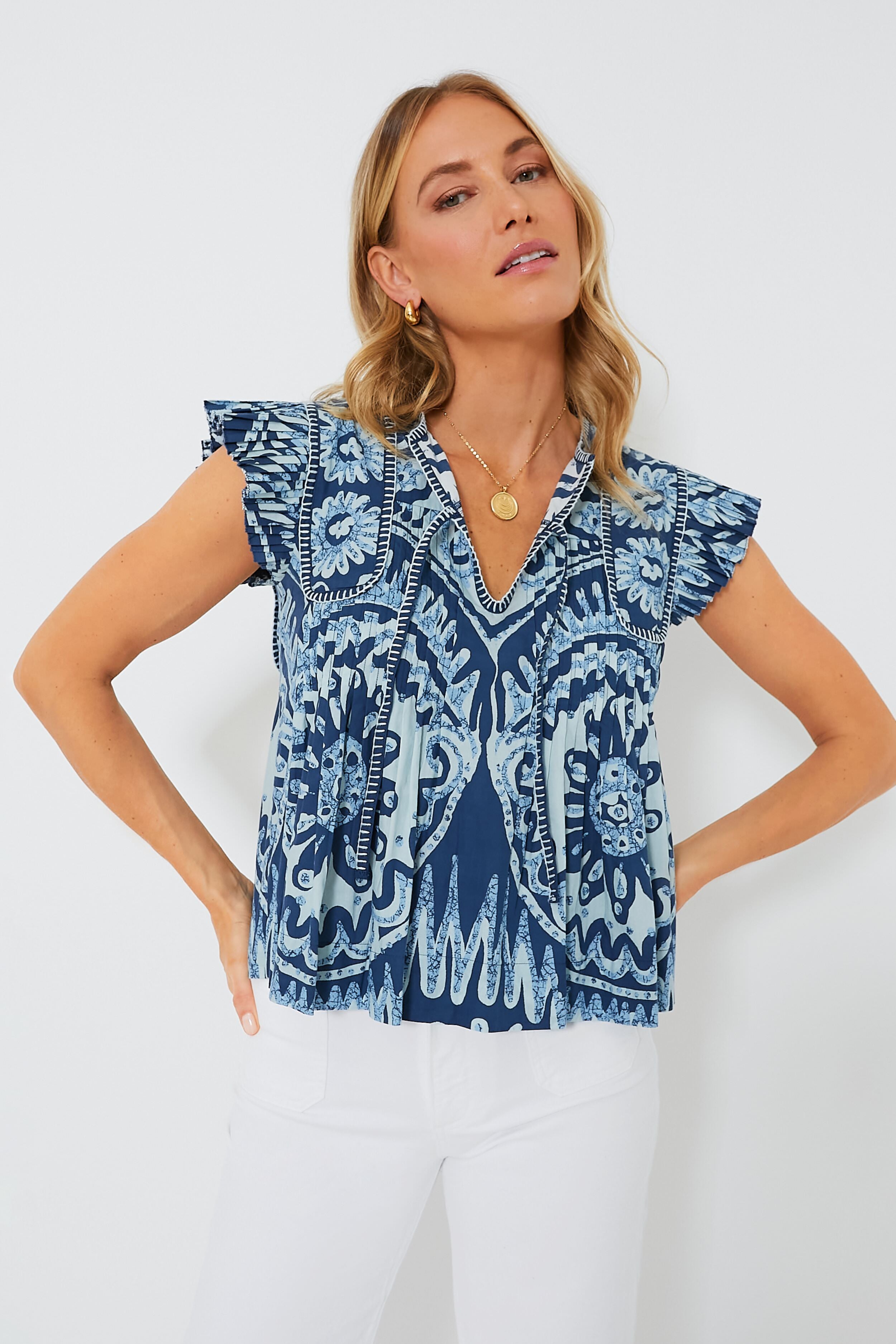 A woman wears a blue patterned Sea New York V-neck tank blouse with white pants, creating a chic and refined look.
