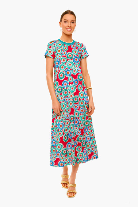 A woman wears a colorful La DoubleJ short-sleeve, ankle-length vintage floral dress with red, blue, and green patterns, paired with gold wedge sandals and a gold bracelet for an Italian-inspired look.