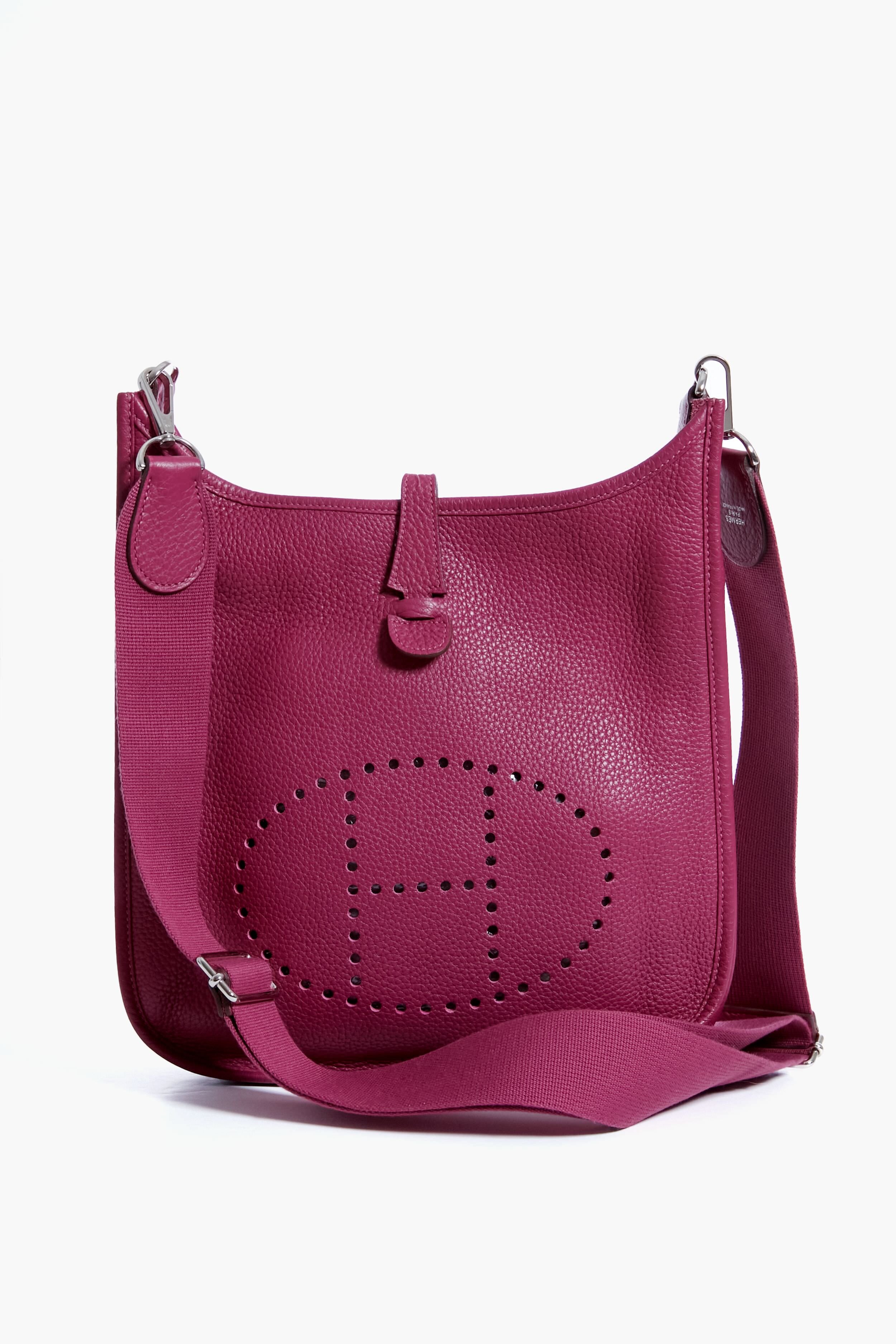 A magenta leather shoulder bag from the Tuckernuck Archive Collection, featuring a perforated oval pattern on the front and a wide matching fabric strap—ideal for lovers of luxury designer accessories.