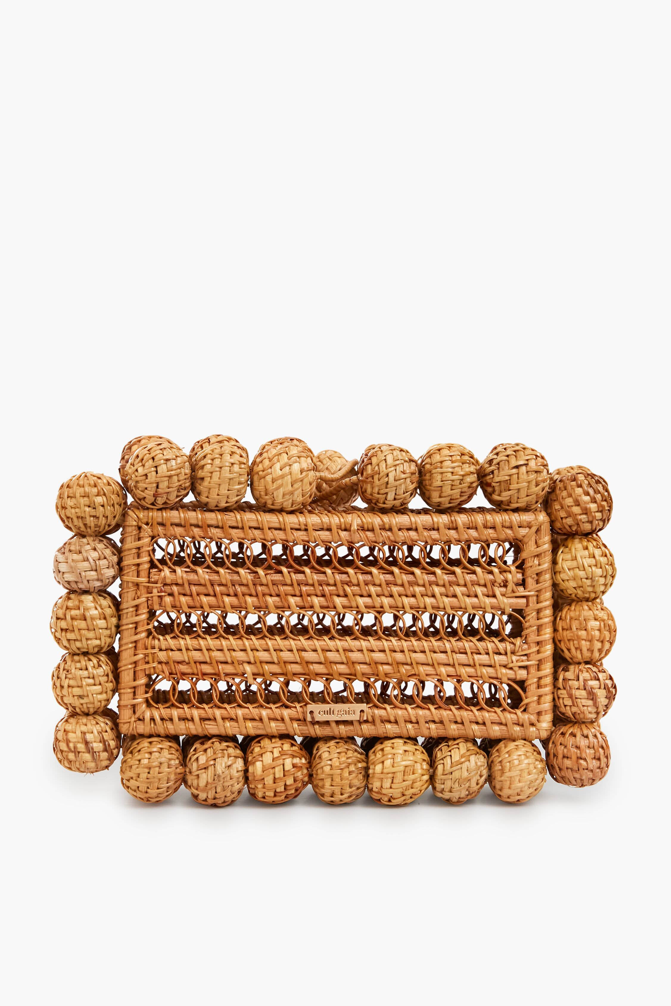 Rectangular woven rattan bag by Cult Gaia, featuring rounded border accents and an intricate braided center pattern.