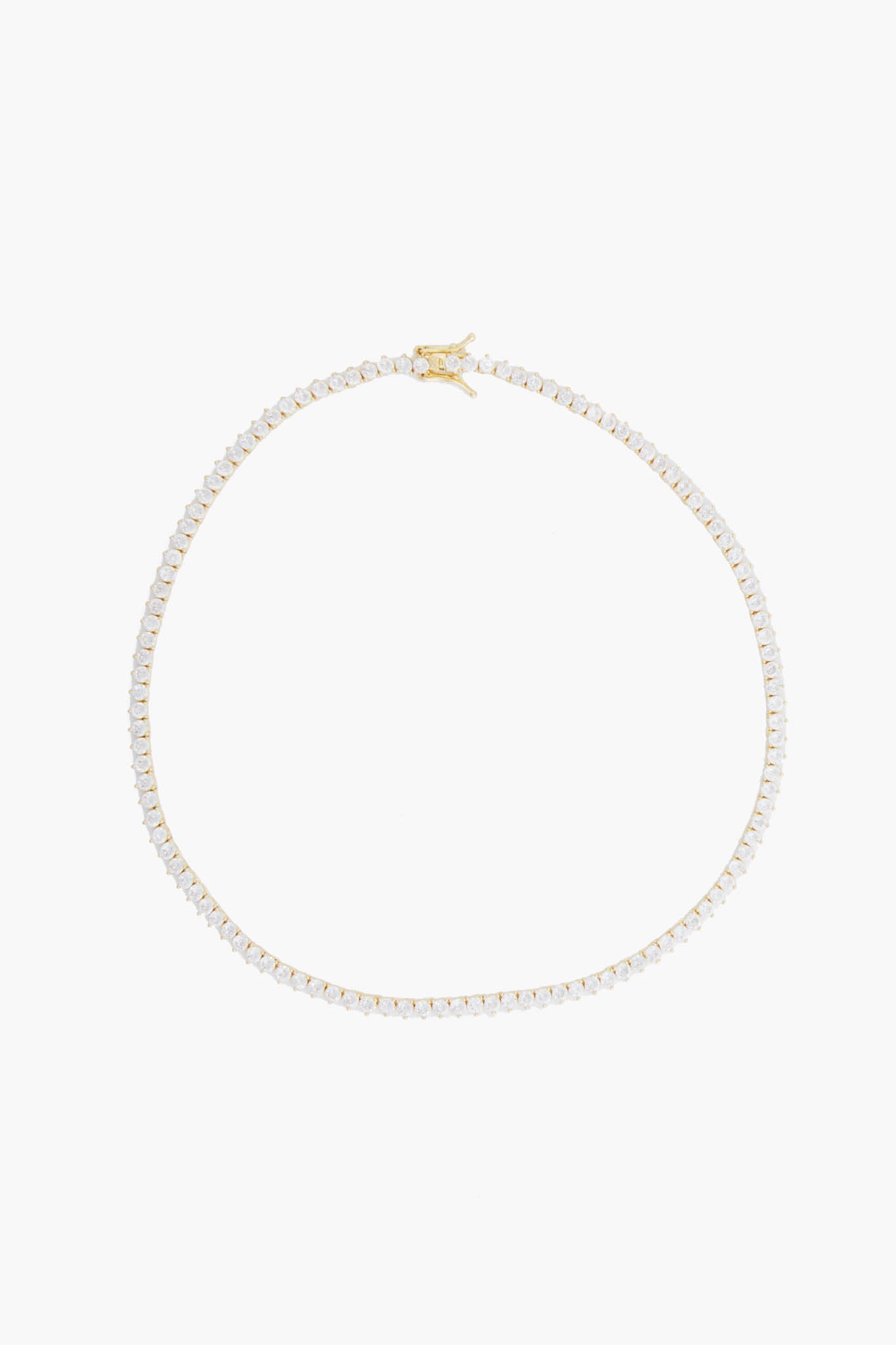 Alexa Leigh's gold tennis necklace features a single row of small, clear gemstones evenly spaced along a 14k gold fill chain, embodying contemporary jewelry style.