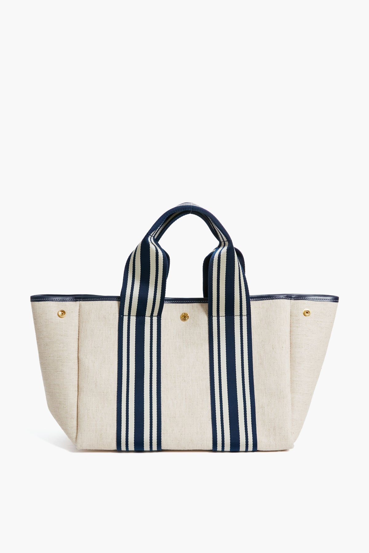 The Rue de Verneuil beige linen tote features navy striped handles, gold-tone buttons, and a structured rectangular shape, making it a stylish and versatile bag for daily essentials.
