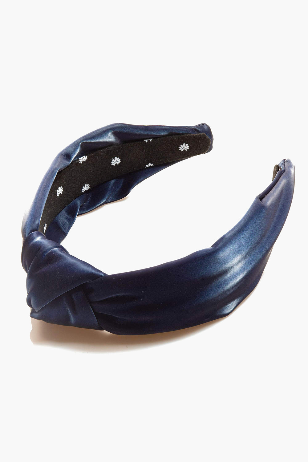 A dark blue satin Lele Sadoughi headband with a twisted knot, black inner lining, and small white floral patterns.