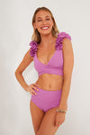 A woman smiles in a Maygel Coronel Radiant Violet Ceres Two Piece, featuring ruffled shoulder straps and high-waisted bikini bottoms.