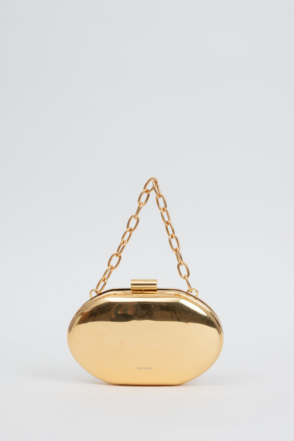 The SIMKHAI gold brushed Sol Metal Oval Clutch features an oval shape and chunky gold chain handle, designed as a modern luxury accessory for women's ready-to-wear outfits.