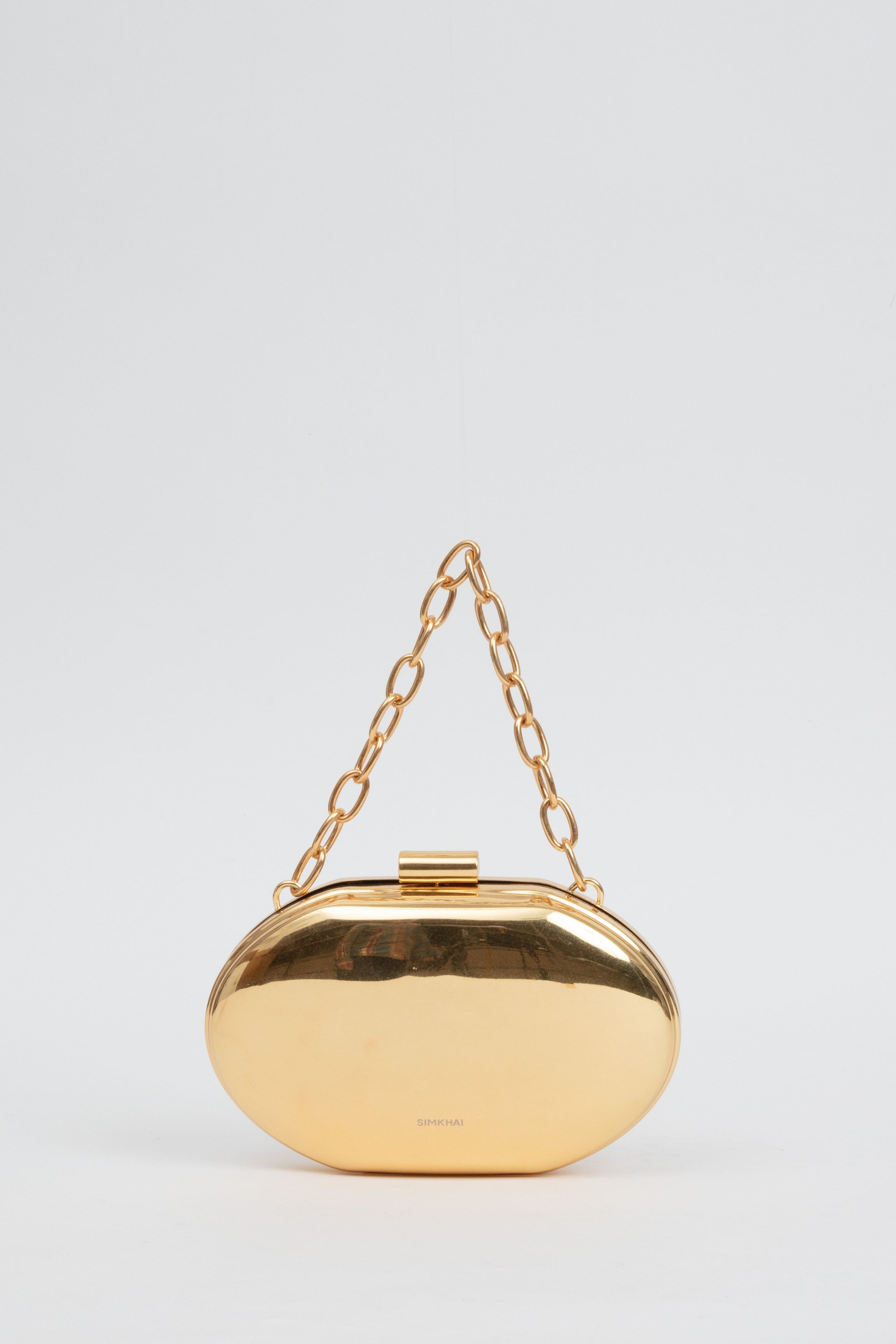 The SIMKHAI gold brushed Sol Metal Oval Clutch features an oval shape and chunky gold chain handle, designed as a modern luxury accessory for women's ready-to-wear outfits.