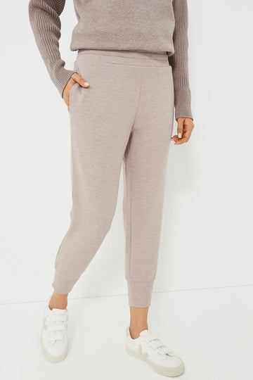 A woman models Varley’s taupe DoubleSoft joggers and matching sweater with white sneakers, epitomizing chic women’s loungewear.