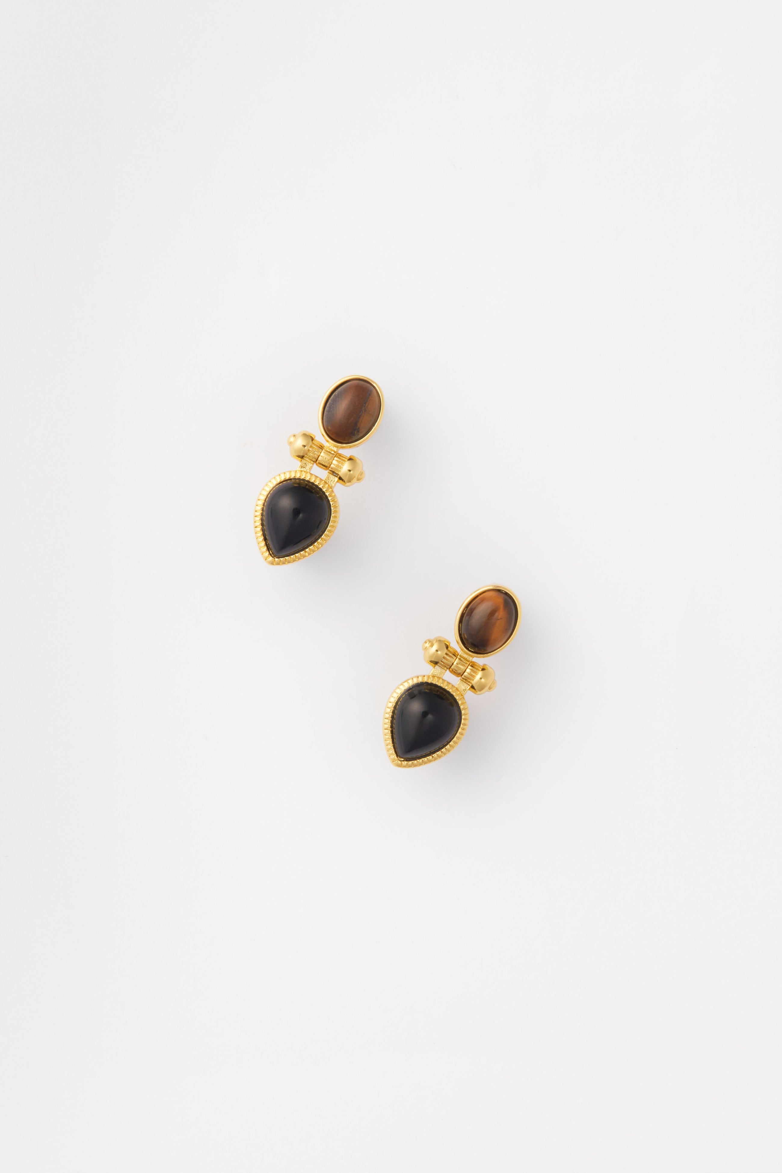 The Petit Moments Gold Rosario Earrings feature gold-trimmed brown ovals and black teardrop stones, making a striking statement.