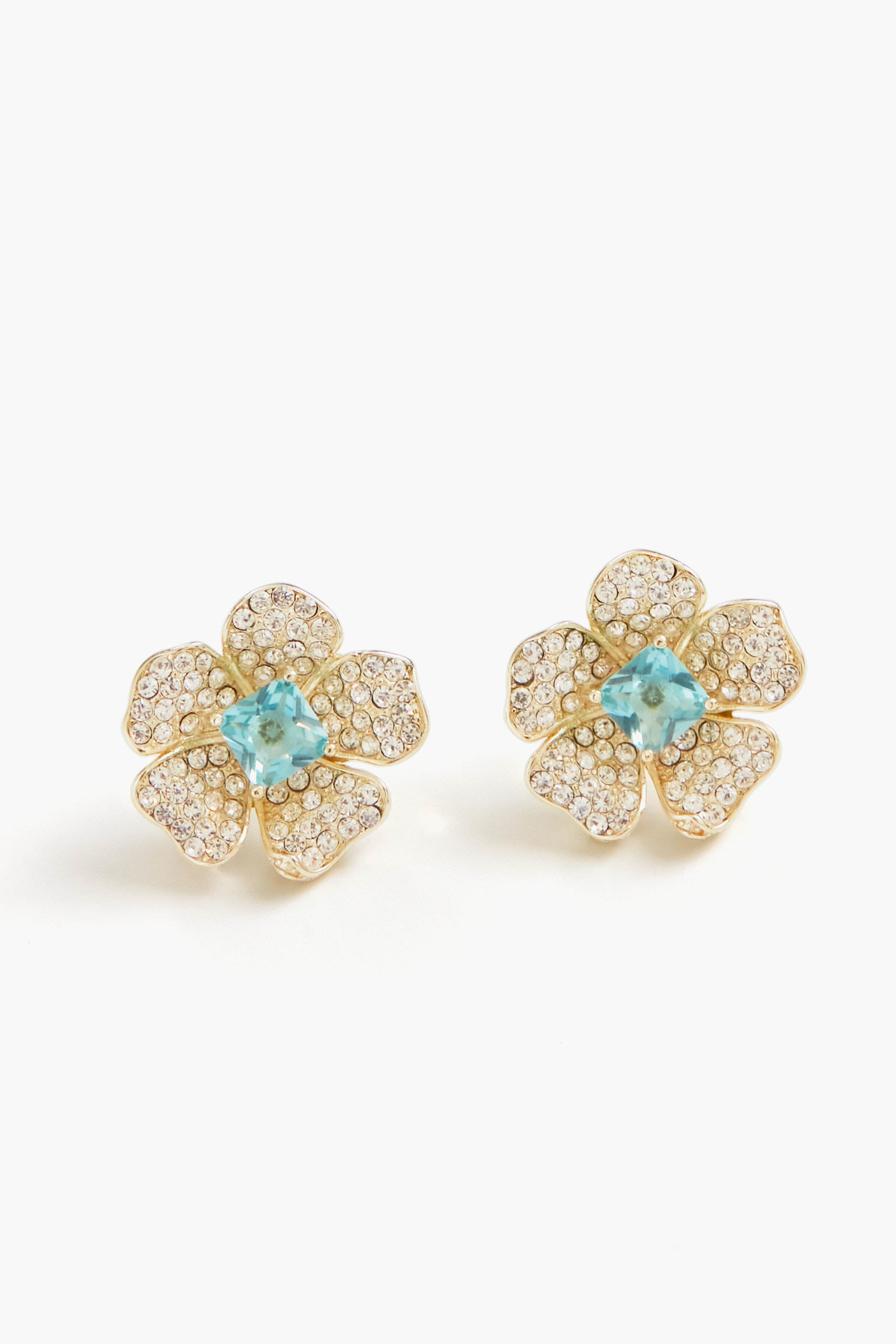Nicola Bathie gold flower studs feature petals encrusted with small clear stones and a London Blue gemstone at the center, crafted in a 14k gold-plated finish.